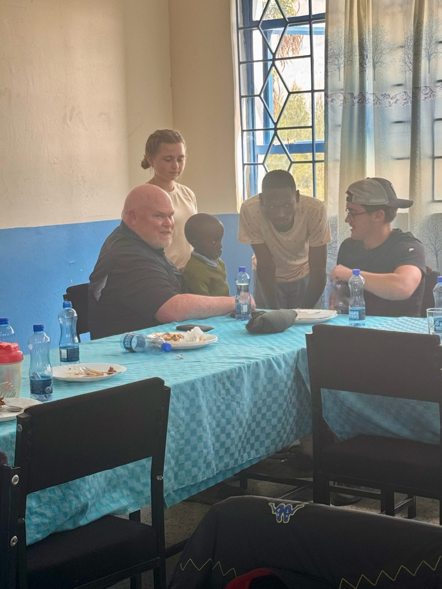 Team members sharing a meal with students and staff around a table