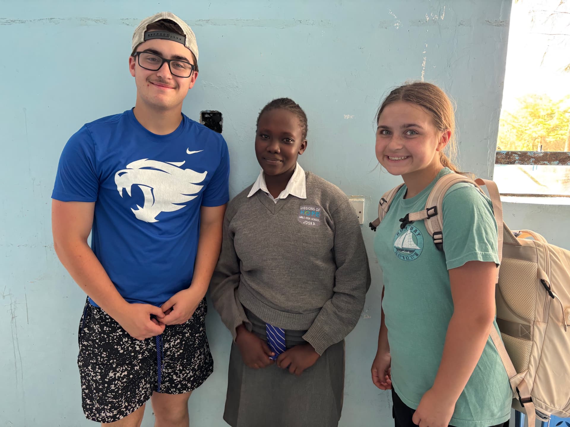 Two team members standing with a student from Missions of Hope Girls High School