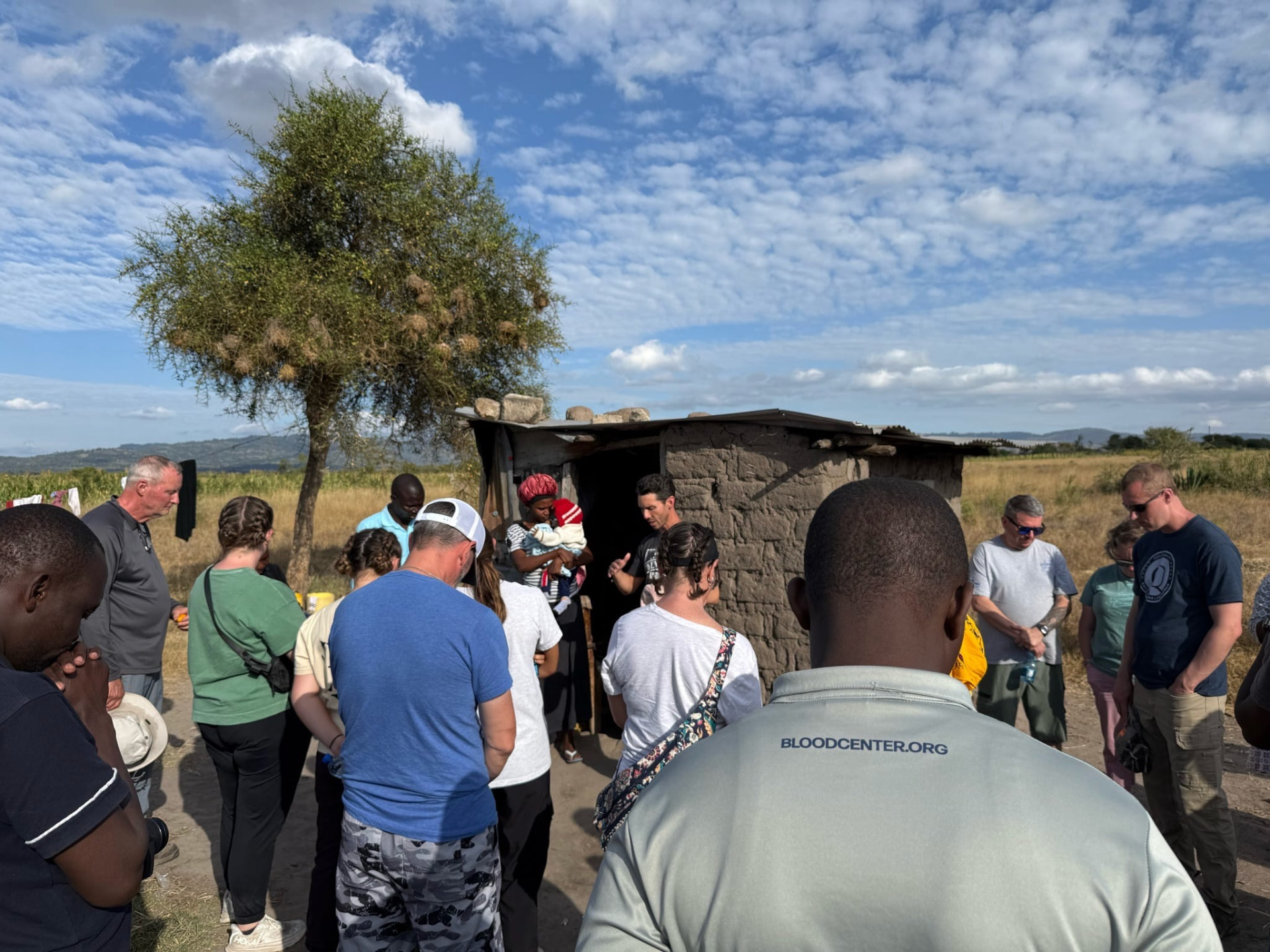 The team praying with a mother outside her home in rural Kenya