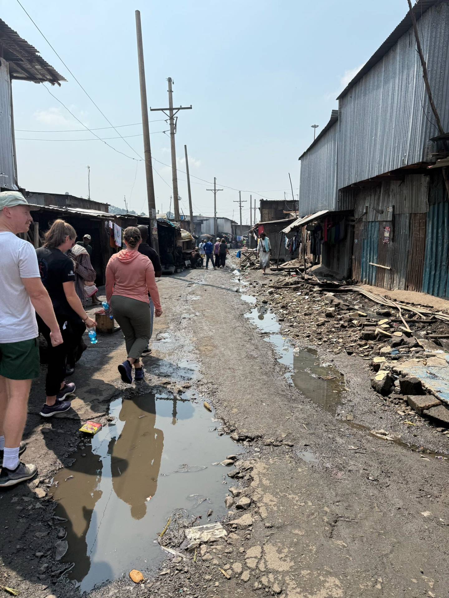 Team members walking a narrow alley between corrugated iron homes
