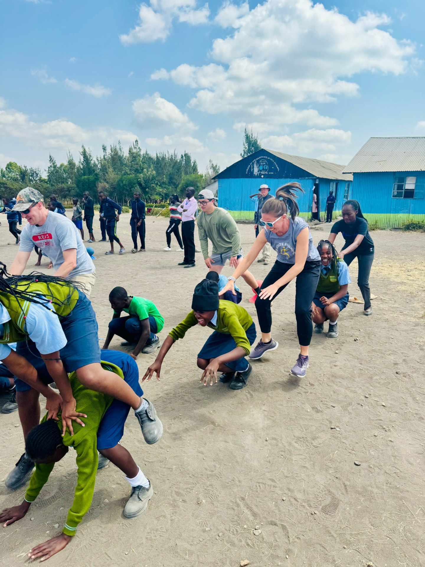 Team members and students mid-game crouching and running on a dirt field