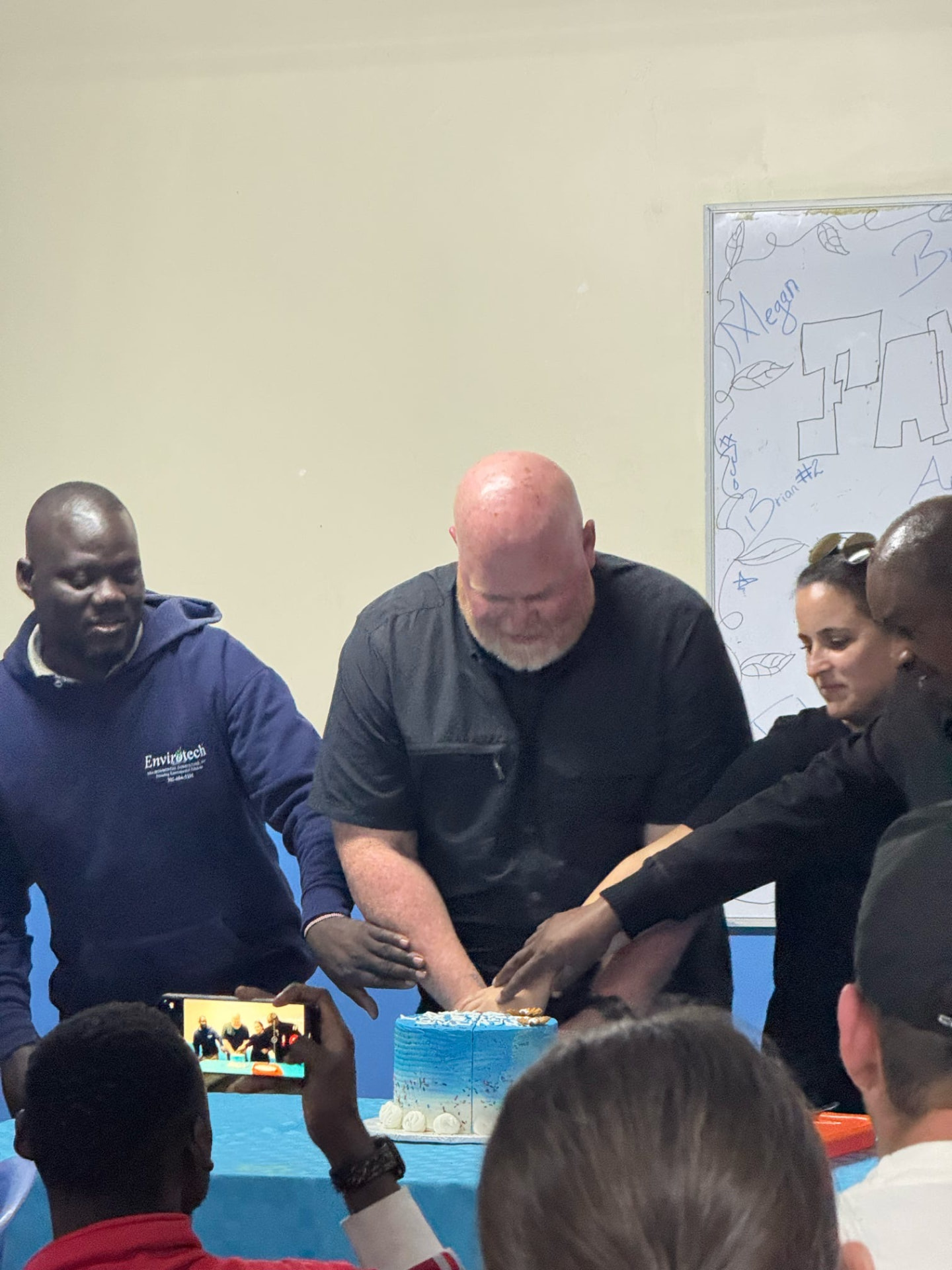 Team members and MOHI staff cutting a celebration cake together indoors