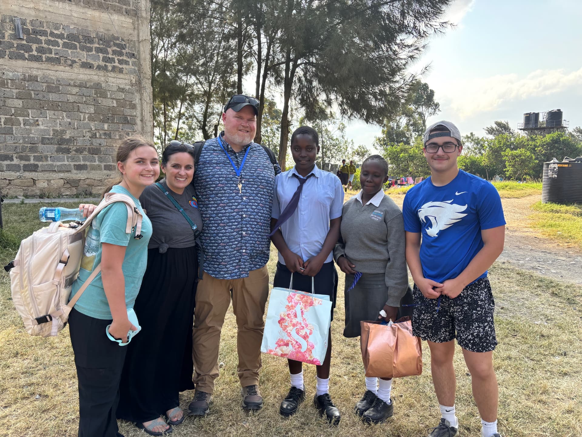 The Whalen family standing with two students outside a stone building